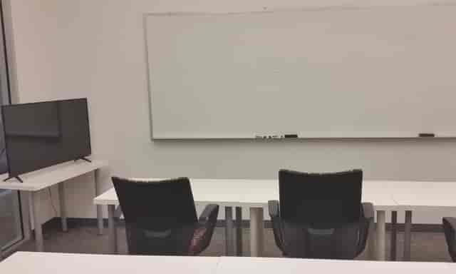 Minimalist conference room with chairs, whiteboard, and TV for professional meetings.