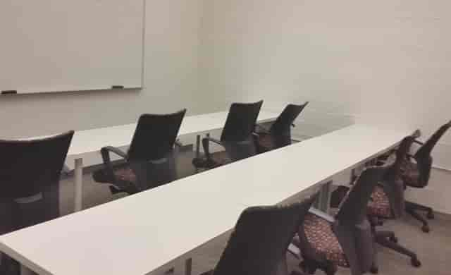 Minimalist conference room with U-shaped tables for workshops and team meetings.