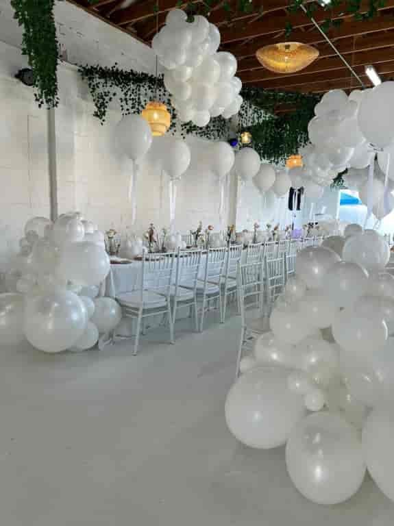 Elegant KUE Ballroom with white decor, floral centerpieces for weddings and upscale events.