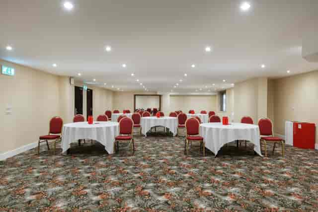 Cambridge Suite at Millennium Gloucester: versatile meeting space with round tables and red chairs.