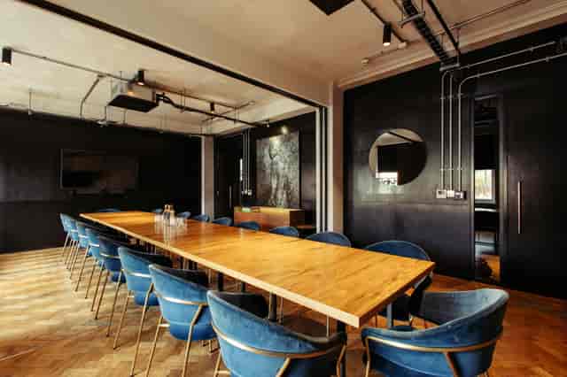 Modern meeting room with wooden table and blue chairs, perfect for corporate workshops.