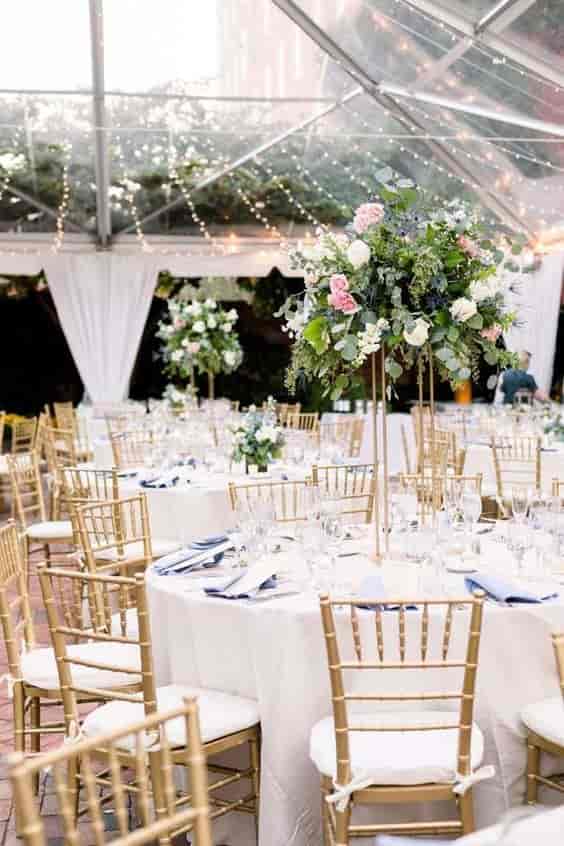 Chiavari chairs at cocktail hour in elegant wedding event space with floral centerpieces.