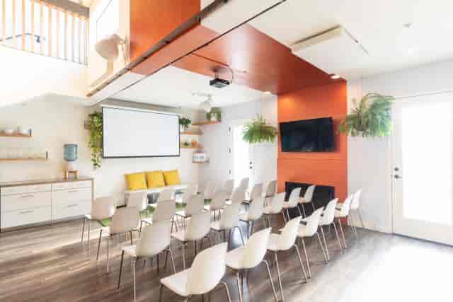 Modern meeting room with white chairs and orange accents, perfect for workshops and team meetings.