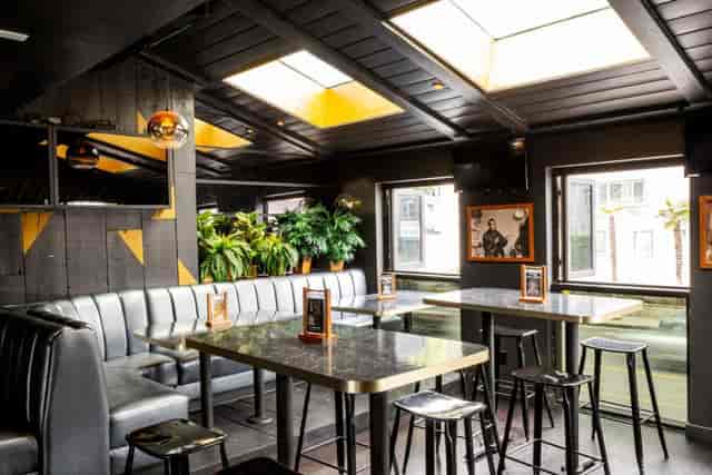 Dance floor at The Naughty Pig, featuring sleek tables and natural light for networking events.