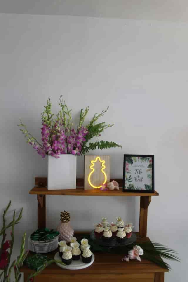 Stylish tropical event setup with modern florals and neon pineapple accent.