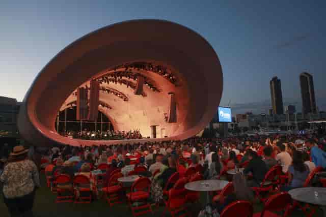 Street Food Pavilion at dusk, vibrant red chairs, outdoor concert venue.