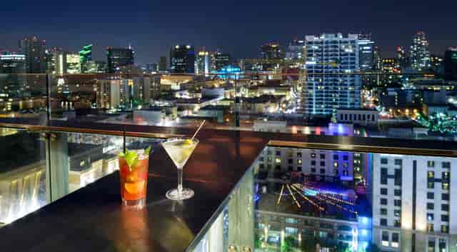 Rooftop city skyline at night with cocktails, perfect for upscale events and networking.