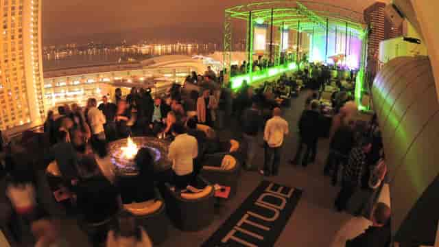 Vibrant rooftop event at Altitude Sky Lounge with city lights and fire pit seating.