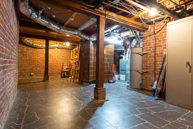 Spacious unfinished basement with exposed brick for unique event spaces or workshops.