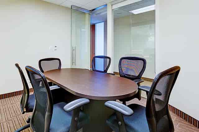Modern conference room with oval table and glass walls for collaborative meetings.