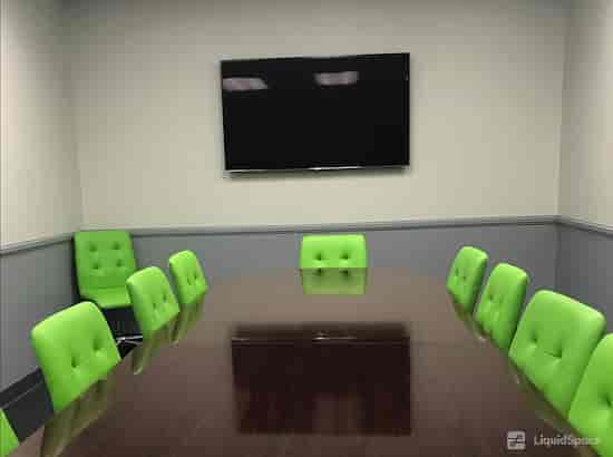 Modern conference room with wooden table and green chairs for meetings and brainstorming.