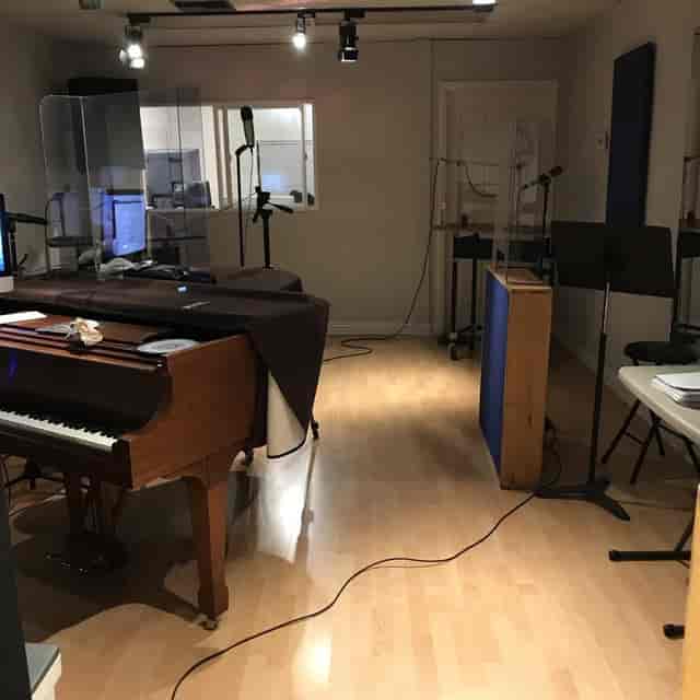 Lockout Suites hybrid meeting space with grand piano, tech setup for events.