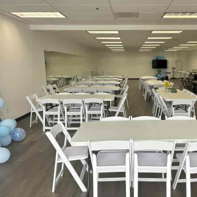 Versatile event space with white tables, perfect for meetings and celebrations.
