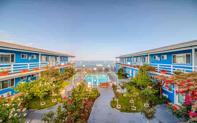 Coastal venue with blue buildings, pool, and ocean views for retreats and gatherings.