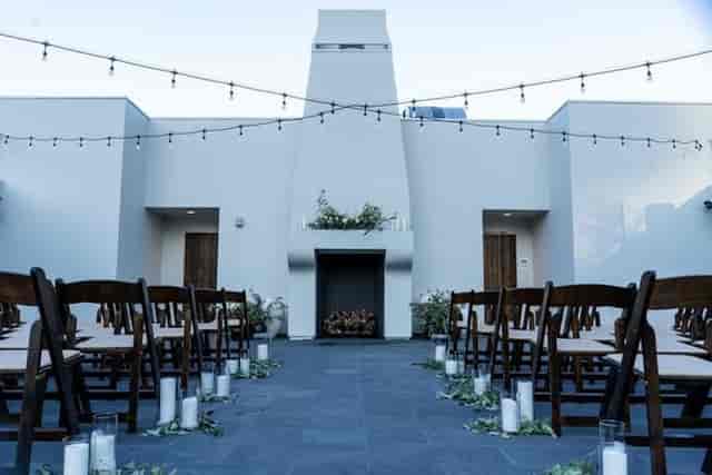 Outdoor wedding venue with elegant wooden chairs and warm string lights.