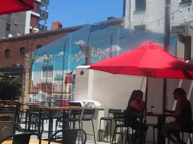 Vibrant outdoor patio with colorful mural and shaded seating for social events.