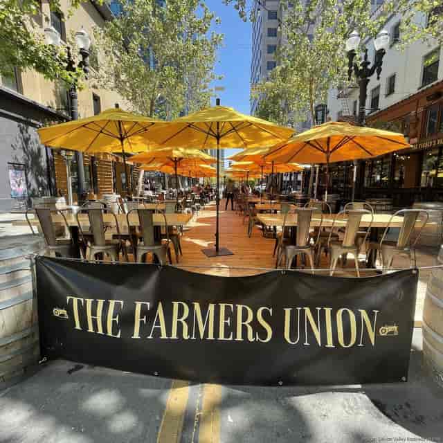Outdoor patio at The Farmers Union with yellow umbrellas, ideal for summer gatherings.