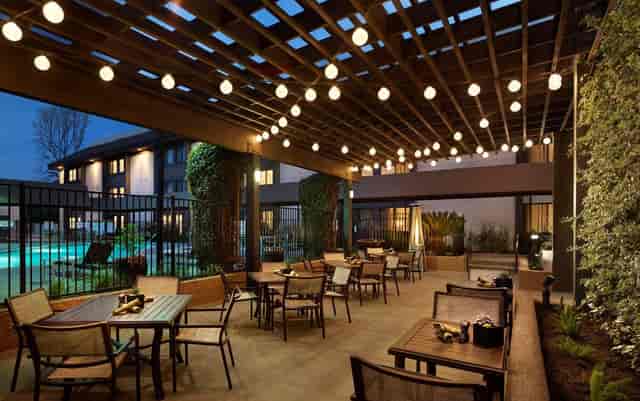 Outdoor event space at Embassy Suites Milpitas with modern furnishings and pool access.