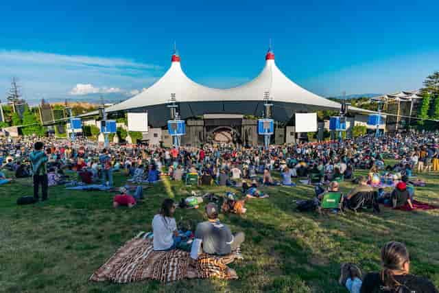 Shoreline Amphitheatre concert hall with audience under iconic tent, vibrant outdoor event.