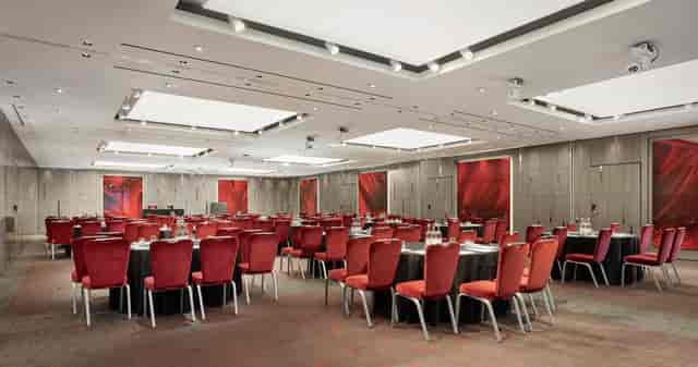 City Suites event space in Park Plaza London, featuring elegant round tables and red chairs.