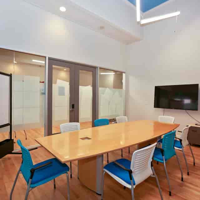 Modern meeting room with wooden table and colorful chairs for team collaboration.