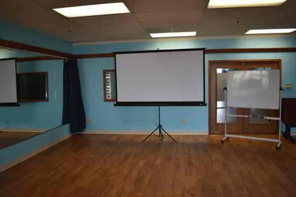 Versatile meeting room with projection screen, ideal for workshops and presentations.