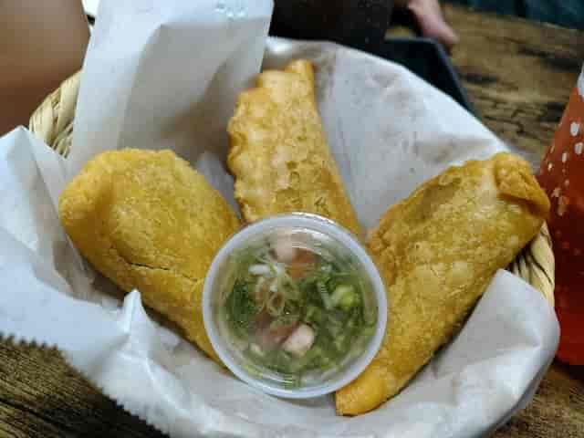 Golden empanadas with dipping sauce at Fonda Colombiana, perfect for events and networking.