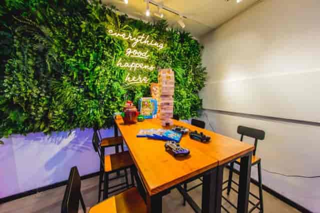 Indoor glasshouse cafe with lush green wall, perfect for team-building events.