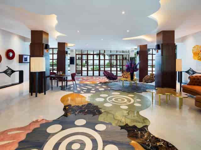 Hybrid meetings in vibrant Sofitel Singapore lobby with artistic flooring, ideal for networking.