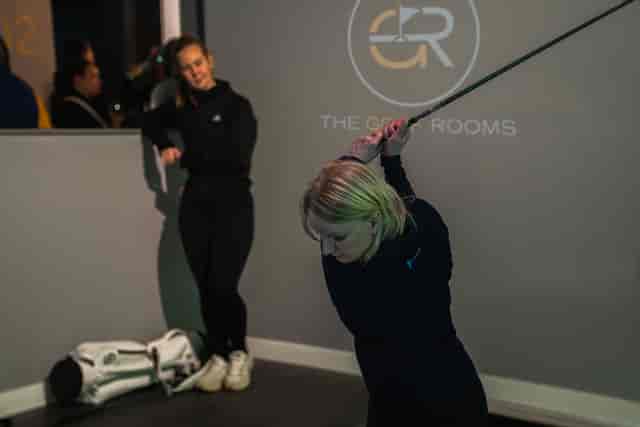 Indoor golf simulator event with participant practicing swing in modern corporate space.
