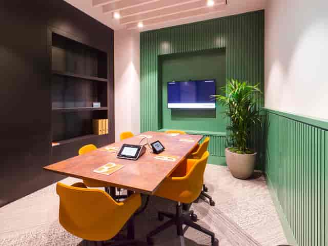 Modern meeting room for rent in Manchester with wooden table and orange chairs.