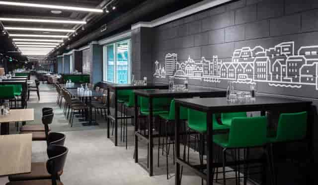 Modern event space at Edinburgh Club, featuring high tables and green chairs for networking.