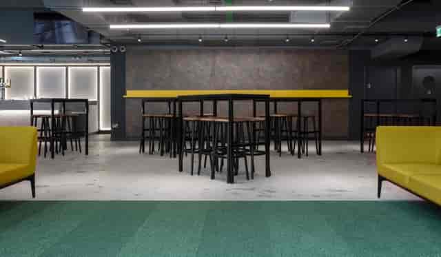 Modern Albion Bar event space with high-top tables and vibrant yellow accents.