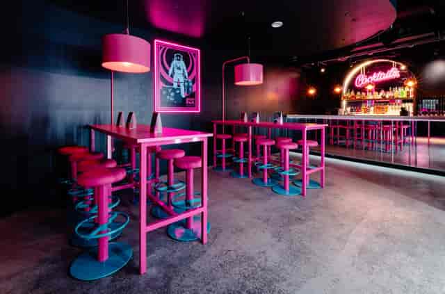 Vibrant event space with pink and blue furniture for private hire at Boom Battle Bar O2.