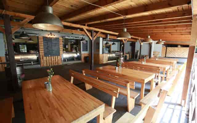 Spacious rustic restaurant venue with wooden beams for casual gatherings and events.