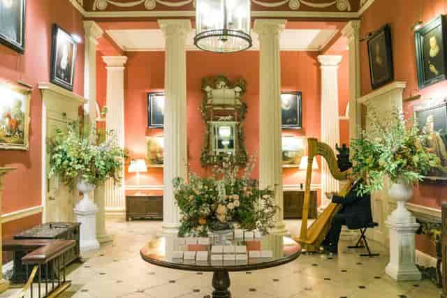 Elegant event space with red walls, floral displays for gala networking at Courteenhall Estate.