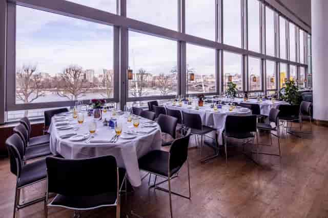 Elegant dining setup with round tables and scenic views for corporate events.