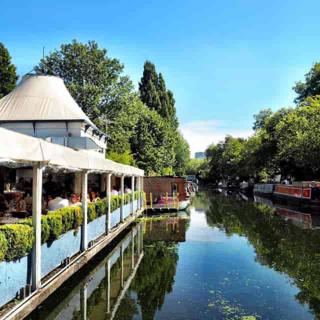 Canal-side restaurant with lush greenery, perfect for summer outdoor events.
