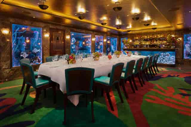 Elegant dining space with aquarium backdrop for exclusive events and corporate dinners.