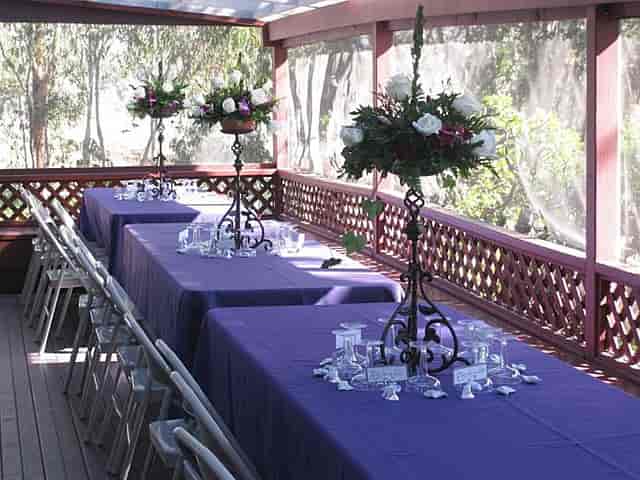 Elegant outdoor event space with purple tables and floral centerpieces at Sweetwater Woman's Club.