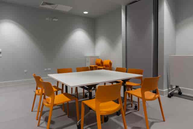 Modern meeting room with white table and orange chairs, perfect for workshops and discussions.