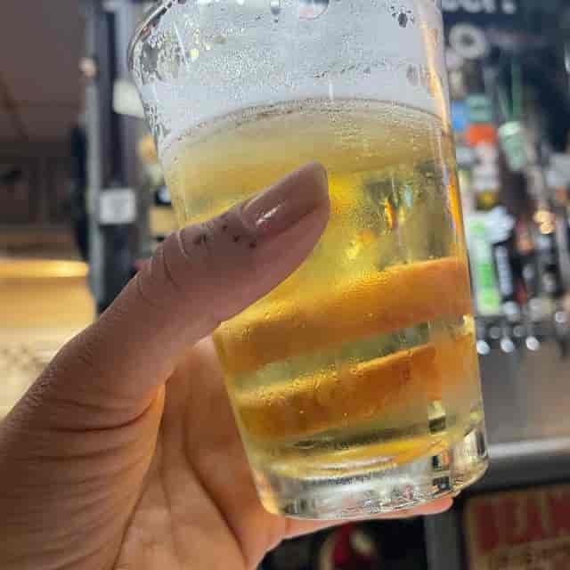 Hand holding a glass of beer at Mission Pizza & Pub for event planning and networking.
