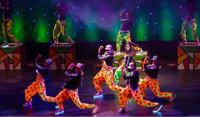 Vibrant dancers in colorful outfits performing at Mona Khan Company's event.