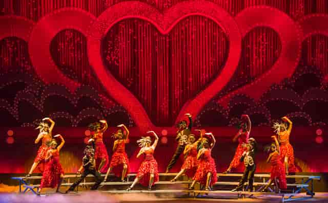 Vibrant dancers in red costumes at Mona Khan Company's Emerging Performers Program event.