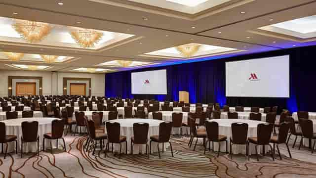 Meeting room with round tables and screens, perfect for corporate events and conferences.