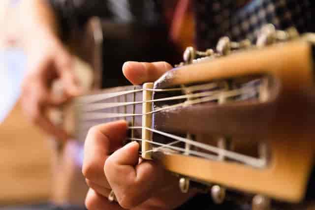 Close-up of a hand playing guitar at Oshman Family JCC for live music events.