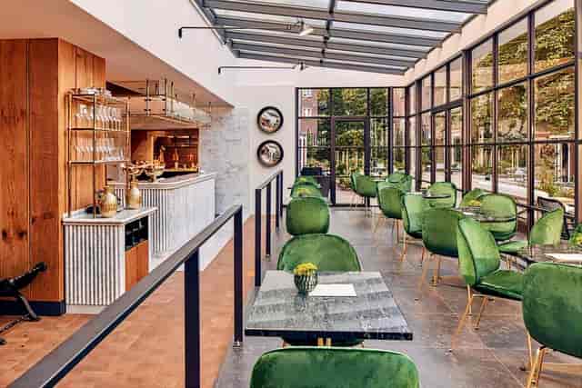 Stylish event space in Pulitzer Amsterdam with green velvet chairs for gatherings.