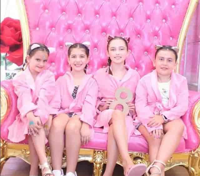 Princess birthday party with girls in pink robes on a luxurious throne backdrop.