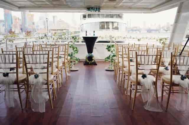 Elegant boat wedding setup with gold chiavari chairs and city skyline backdrop.