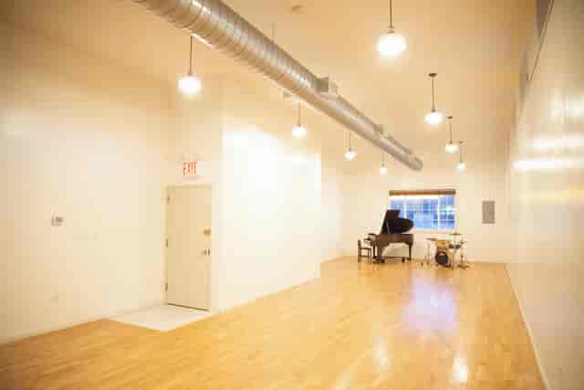 Versatile event space in Greenpoint Hall with natural light and grand piano for gatherings.